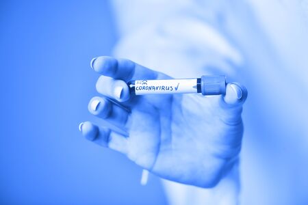 Nurse holding a positive blood test result for the new rapidly spreading Coronavirus. Blue filter.の写真素材