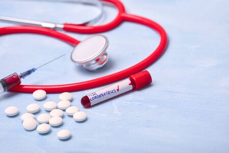 Positive virus Coronavirus blood test, pills, syringe and stethoscope on blue copy space background for a bannerの写真素材