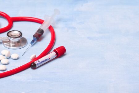 Virus Coronavirus blood test, pills, syringe and stethoscope on blue copy space background for a bannerの写真素材
