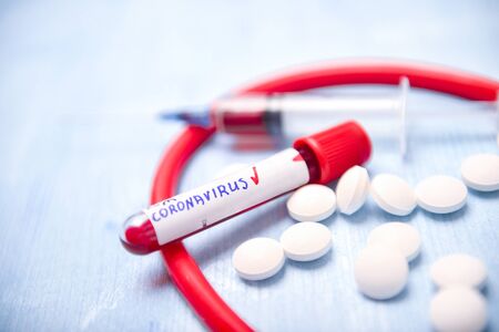 Virus Coronavirus blood test, pills, syringe and stethoscope on blue copy space background for a bannerの写真素材