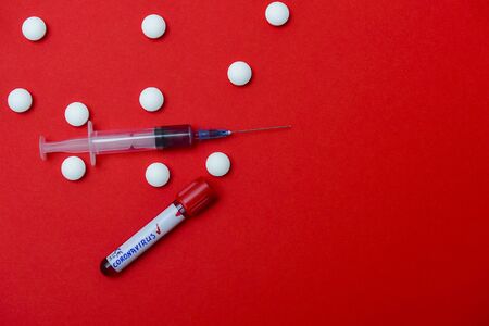 Virus Coronavirus blood test, pills, syringe on red copy space background for a bannerの写真素材