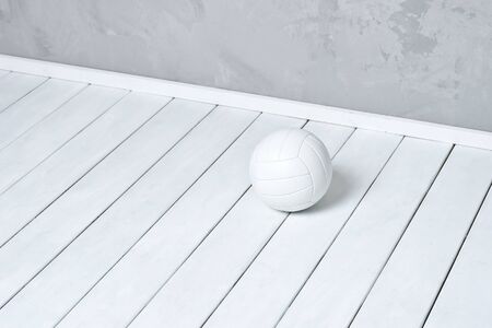White volleyball lying on wooden surface near grey wall with copy spaceの写真素材
