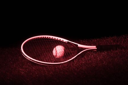Tennis racket with tennis balls on grass with black background and copy space. Red filterの写真素材