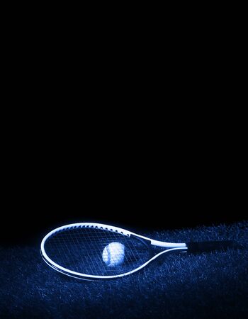 Tennis racket with tennis balls on grass with black background and copy space. Blue filterの写真素材