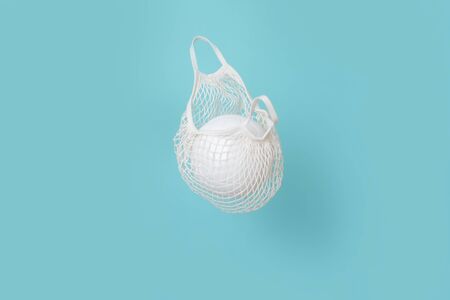 White mesh bag with volleyball on air. Blue background with copy space.の写真素材