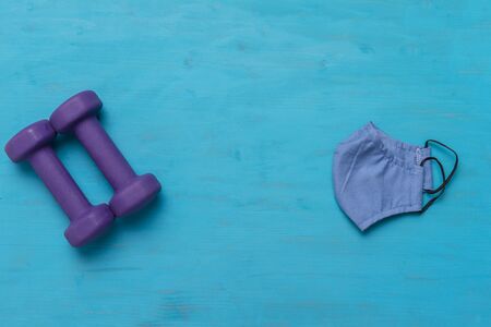 Dumbbells and mask on blue wooden background. Safe sport concept.の写真素材