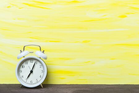 White alarm clock on yellow backgroundの写真素材
