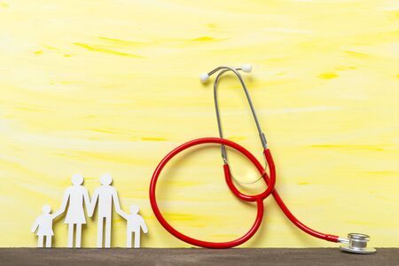 Family paper cut out with red stethoscope on yellow backgroundの写真素材