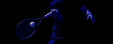 Male tennis player in action on the court on a sunny day. Blue color filterの写真素材