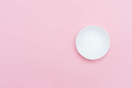 Empty white ceramic round plate isolated on pinkの写真素材