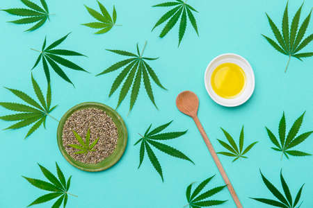 Green marijuana leaf, hemp seeds, wooden spoon and cannabis oil on mint color background. Alternative medicine. Vegetarian food conceptの写真素材