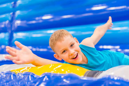 Little boy on colorful playground trampoline. Kids jump in inflatable bounce castle on kindergarten birthday party. Activity and play center for young child.の写真素材