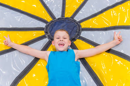 Child on colorful playground trampoline. Kids jump in inflatable bounce castle on kindergarten birthday party. Excited kid having fun at game center.の写真素材
