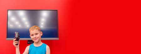 Little boy playing video game in the red room. Television and video game addiction.