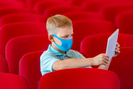 School kid with blue mask against virus and tablet at lesson. Safe back to school during pandemic...
