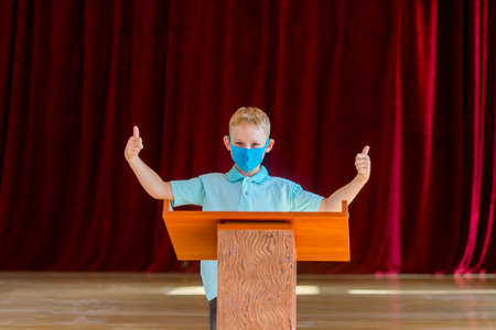 School kid with blue mask against virus and tablet at lesson. Safe back to school during pandemic concept. Social distancing to fight COVID-19の写真素材