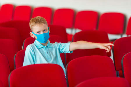 School kid with blue mask against virus and tablet at lesson. Safe back to school during pandemic concept. Social distancing to fight COVID-19の写真素材