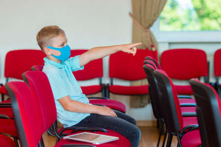 School kid with blue mask and  ball in a physical education lesson. Safe back to school during pandemic concept. Social distancing to fight COVID-19の写真素材