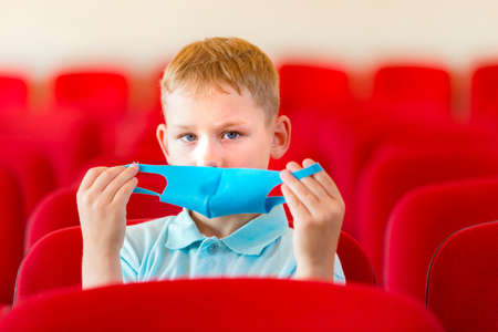 School kid with blue mask against virus and tablet at lesson. Safe back to school during pandemic concept. Social distancing to fight COVID-19の写真素材