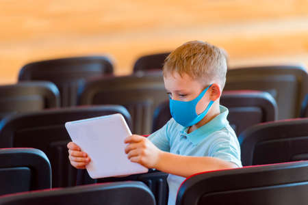 School kid with blue mask and  ball in a physical education lesson. Safe back to school during pandemic concept. Social distancing to fight COVID-19の写真素材