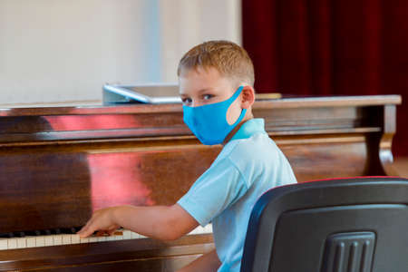 School kid with blue mask and  ball in a physical education lesson. Safe back to school during pandemic concept. Social distancing to fight COVID-19の写真素材