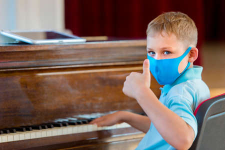 School kid with blue mask and  ball in a physical education lesson. Safe back to school during pandemic concept. Social distancing to fight COVID-19の写真素材