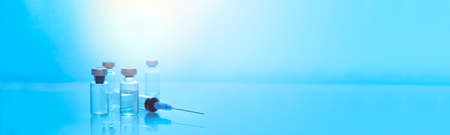 Injectable medications in sealed vials and a disposable plastic medical syringe. Blue color filterの写真素材