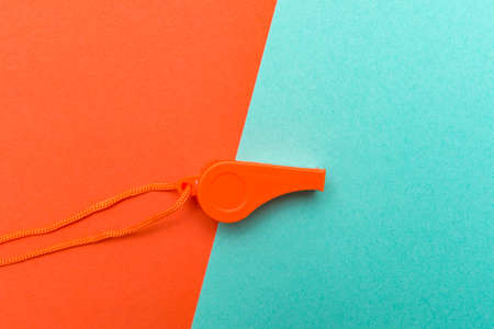 Orange sports whistle on orange and mint background. Concept- sport competition, referee, statistics, challenge. Basketball, handball, futsal, volleyball, soccer, baseball, football and hockey referee whistleの写真素材