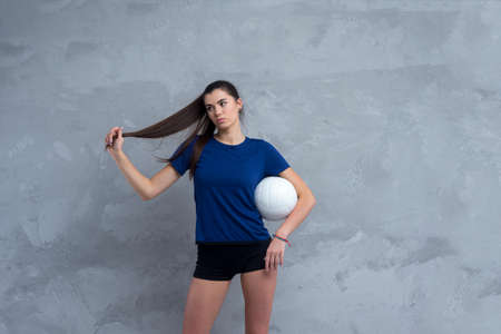 Volleyball girl hold white ball on grey background. Player doing sport workout at home Sport and recreation concept.の写真素材