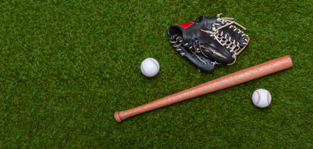 Baseball bat, glove and ball on green grass field.  Sport theme background with copy space for text and advertismentの写真素材