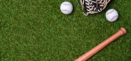 Baseball bat, glove and ball on green grass field.  Sport theme background with copy space for text and advertismentの写真素材