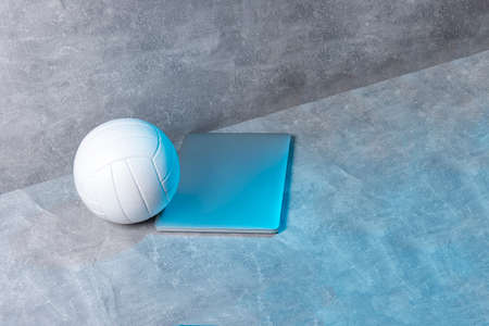 White Volleyball ball and grey laptop on grey background. Online workout conceptの写真素材