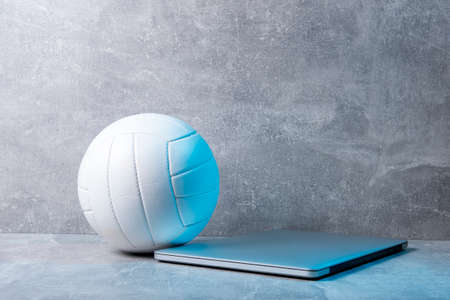 White Volleyball ball and grey laptop on grey background. Online workout conceptの写真素材