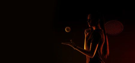 Beautiful girl tennis player with a racket on dark background wiht color lights. A sports coach leads an online lesson. Online workout conceptの写真素材
