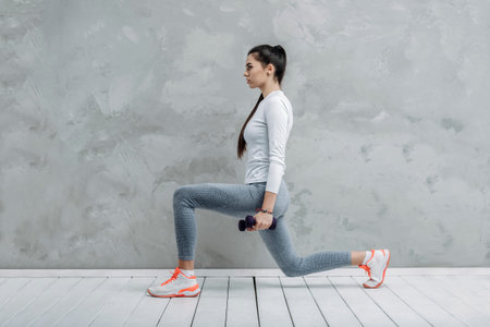 Fitness girl training isolated on grey background. A sports coach leads an online lesson. Online workout conceptの写真素材