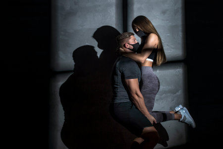 Young couple working out in gym post corona outbreak, wears protective face mask.  Loving couple making exercising in gymの写真素材
