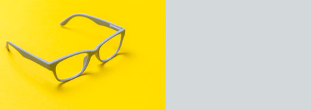 Grey glasses on a yellow and grey background. Top view, space for your text