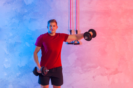 Athletic trainer with black dumbbells and rubber resistance bands teaches group fitness and work out online training on a bright neon background. Sport online conceptの写真素材