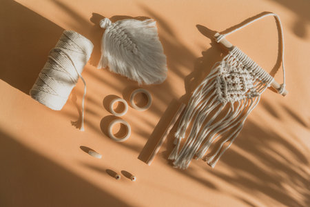 Macrame accessories on beige background. Creative hobby concept. Top view. Vintage color filter