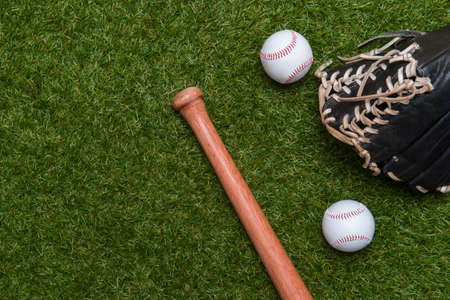 Baseball bat, glove and ball on green grass field.  Sport theme background with copy space for text and advertismentの写真素材