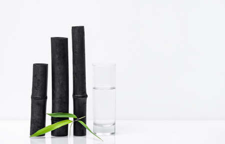 Bamboo charcoal water filter sticks, green leaf and glass of water. Natural bamboo charcoal is a powerful purifier which refreshes tap waterの写真素材