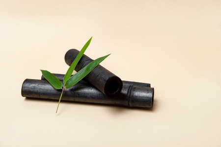 Bamboo activated charcoal stick and green leaf on beige backgroundの写真素材