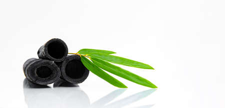 Bamboo activated charcoal sticks and green leaf isolated on white background.の写真素材