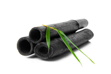 Bamboo activated charcoal sticks and green leaf isolated on white background.の写真素材