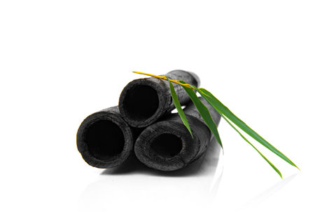 Bamboo activated charcoal sticks and green leaf isolated on white background.の写真素材
