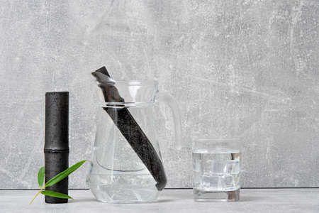 Bamboo charcoal water filter stick, green leaf and glass of water. Natural bamboo charcoal is a powerful purifier which refreshes tap waterの写真素材