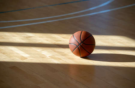 Basketball on hardwood court floor with natural lighting. Workout online conceptの写真素材