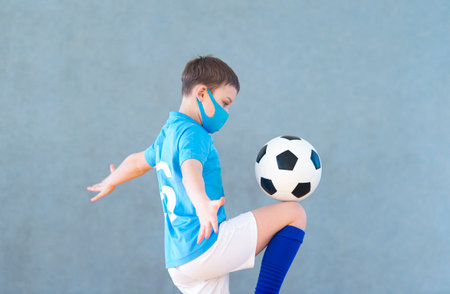 School kid with mask and soccer ball in a physical education lesson. Safe back to school during pandemic conceptの写真素材