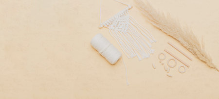 Macrame accessories on beige background. Creative hobby concept. Top view. Vintage color filter