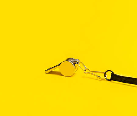 Sports whistle on yellow background. Concept - sport competition, referee, statistics, challenge. Basketball, handball, futsal, volleyball, soccer, baseball, football and hockey referee whistleの写真素材